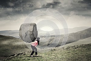 Woman carrying a rock on mountain