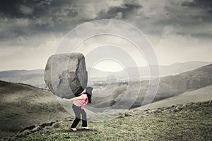 Woman carrying a rock on mountain photo