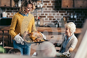 woman carrying thanksgiving turkey for family dinner while her senior mother looking