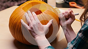 Woman carving Jack O Lantern pumpkin for Halloween