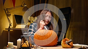 Woman carving Jack O Lantern pumpkin for Halloween