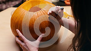 Woman carving Jack O Lantern pumpkin for Halloween