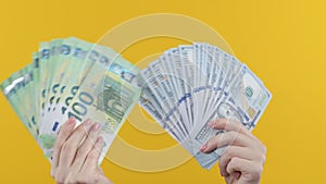 Woman with cash money - USD and EUR currency dollars euros banknotes on yellow background. Jackpot, lottery prize