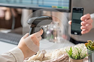 Woman cashier scanning qr code from buyer phone using barcode scanner. Man buying a gift in a female clothing store