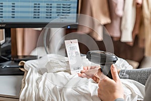 Woman cashier, seller scanning and reading  barcode from clothes using barcode scanner in female clothing store.