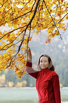 Woman casually dressed near the branches of an autumn tree