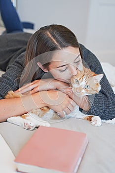 Woman, cat and kiss on bed in home for love, care and bonding together to relax in the morning. Girl, pet and hug cute