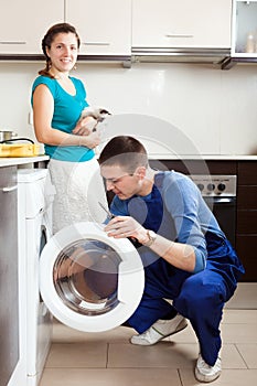 Woman with cat watching as worker repairing washing machine