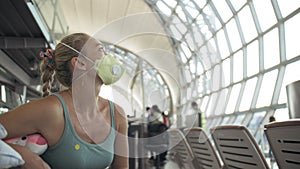 Woman caucasian at airport with wearing protective medical mask on head against the background of the plane. Coronavirus