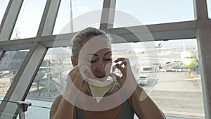 Woman caucasian at airport with wearing protective medical mask on head against the background of the plane. Coronavirus