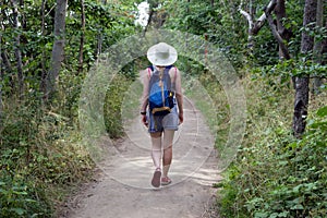 Woman, caucasian beauty style, blonde girl backpacking on a path through the forest