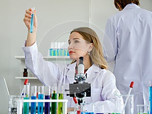 Žena kaukazský sú vedec pozrite na vzorka v rúrka a vedec muž stojace na v laboratórium 