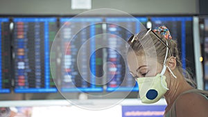 Woman caucasian at Suvarnabhumi Airport with wearing protective medical mask. Flight Information Board. Coronavirus sars