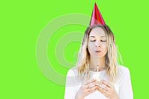 A Woman Celebrates Her Birthday with a Cupcake and Candle with a Party Hat on Green Screen