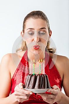 Woman celebrating birthday with cake blowing candles out