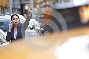 Woman on Cell Phone Hailing a Yellow Taxi Cab photo