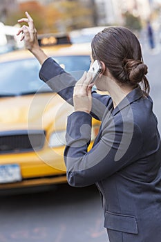 Woman on Cell Phone Hailing a Yellow Taxi Cab photo