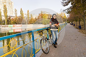 Woman with Cell Phone Leaning on Railing in Park