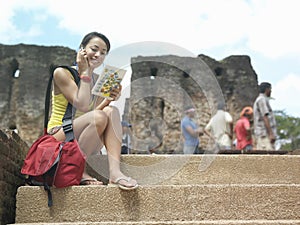 Woman With Cellphone And Guidebook Against Old Ruins photo
