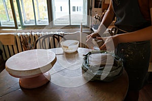 Woman ceramics artist molding raw clay for sculpturing pottery on potter wheel. Female art teacher