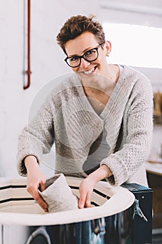 Woman in ceramics workshop putting vessel into kiln