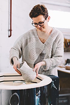 Woman in ceramics workshop putting vessel into kiln