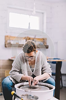 Woman in ceramics workshop working on pottery wheel