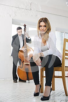 Woman on chair and man plays melody