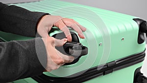 A woman changes a broken wheel on a mint plastic suitcase. Replaceable fittings for the luggage bag.