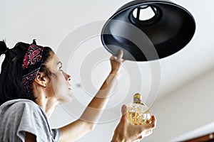 Woman changing lightbulb at home