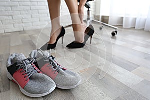Woman changing shoes in office, closeup with focus on sneakers. Tired feet after wearing high heels