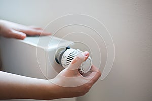 Woman changing the temperature on radiator by temperature controller, increase or decrease the price of heating