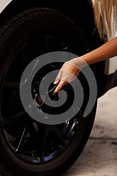 Woman is changing tire of car with wheel wrench photo