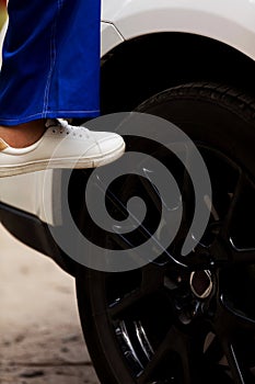 Woman is changing tire of car with wheel wrench photo