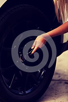 Woman is changing tire of car with wheel wrench photo