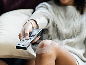 Woman changing TV channel with remote controller