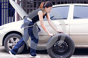 A woman is changing tyre of car for automotive maintenance service