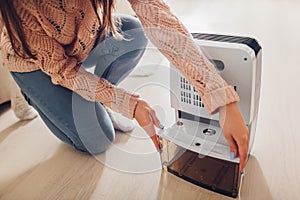 Woman changing water container of dehumidifier at home. Dampness in apartment. Modern air dryer