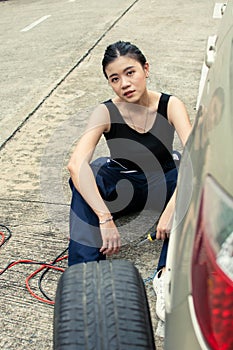 A woman is chaning tyre of car