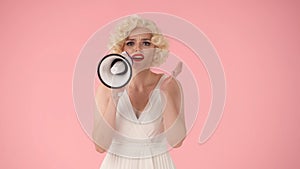 Woman in character of Marilyn Monroe speaking into megaphone. Woman with colorful makeup, wig and white dress in studio