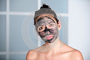 Woman with charcoal facial mask. Beautiful young woman with facial black mud clay mask. Skin care and treatment, spa