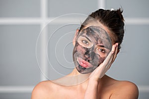 Woman with charcoal facial mud mask on face. Cosmetic procedure. Beauty spa and cosmetology. Spa woman applying gray