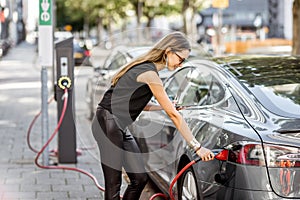 Woman charging electric car outdoors