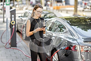 Woman charging electric car outdoors