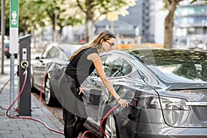 Woman charging electric car outdoors