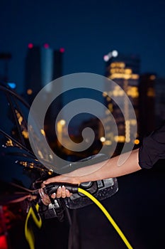 Woman charging an electric car during working night hours in a business center