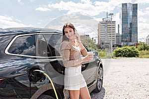 Woman charging an EV car in an electric vehicle parking lot