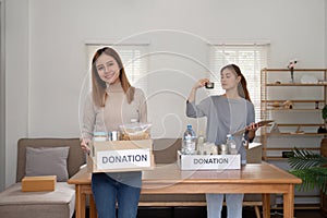 Woman with charity box and group of volunteers at assistance center. Charity, donation, and volunteering concept