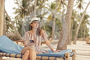 Woman chatting online with friends while relaxing on the beach