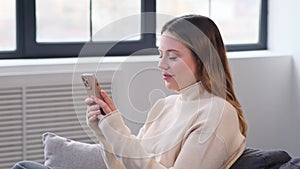 Woman Chatting In Social Media And Laughing Using Smartphone At Home